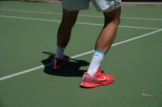 What socks do tennis players use? image with player serving and wearing men's tennis socks