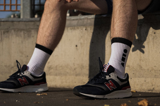 Clay Active sport socks blog post image. White and black clay active sport sock, sitting down on basketball court. Are Australian made socks better? Clay Active finds that sport socks made in Australia are softer, more comfortable and more durable. 