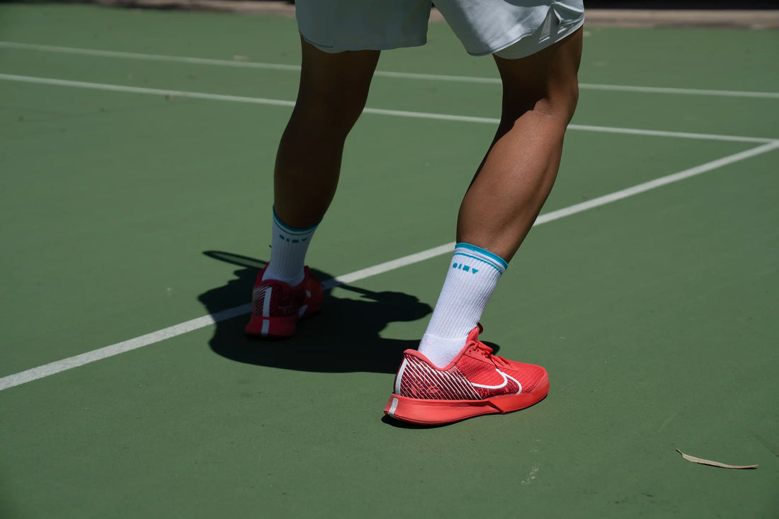 What socks do tennis players use? image with player serving and wearing men's tennis socks