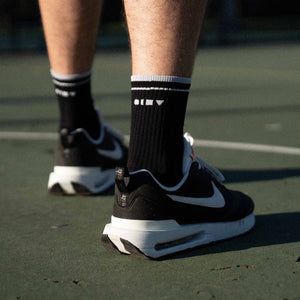Men's black tennis socks on court. Made in Australia.