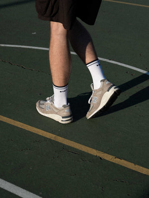 Clay Active men's white tennis socks with New Balance shoes on court.