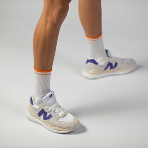 Men's orange and white tennis socks with New Balance shoes.